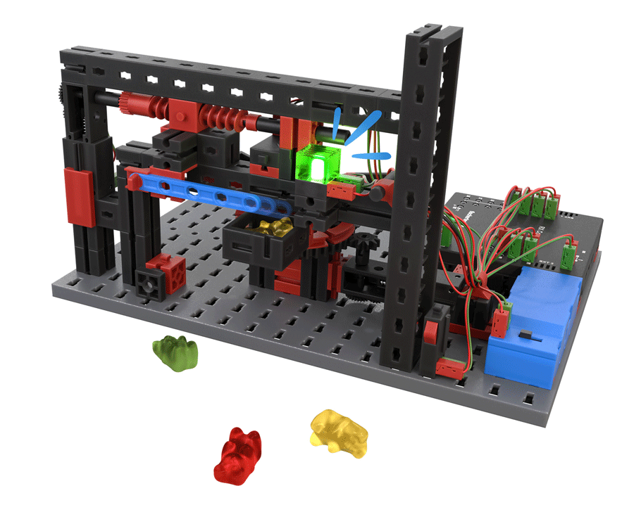 Technisches Modell eines Süßigkeitenautomaten aus einem fischertechnik-Bausatz, mit Verkabelung und Gummibärchen als Beispielobjekte.