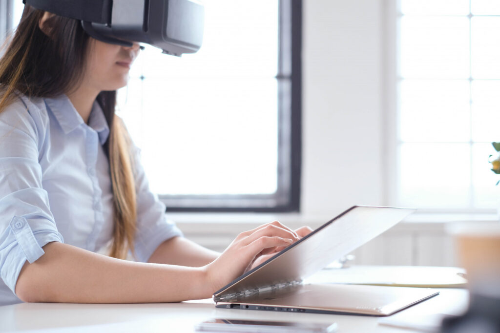Schülerin mit VR-Brille arbeitet am Laptop