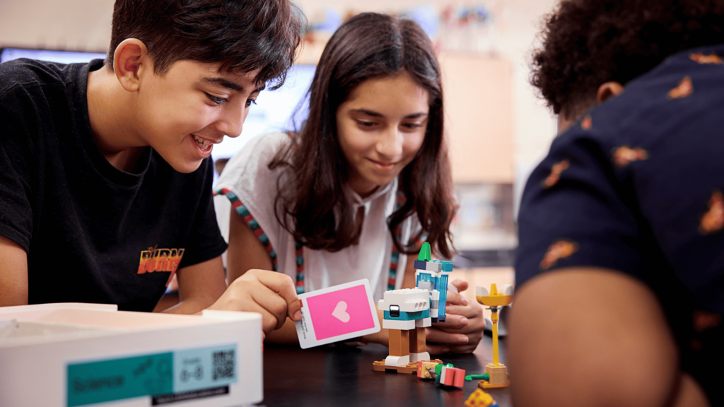 Zwei Schüler interagieren mit einem LEGO® Education Naturwissenschaften Modell und zeigen eine Karte mit einem Herzsymbol.