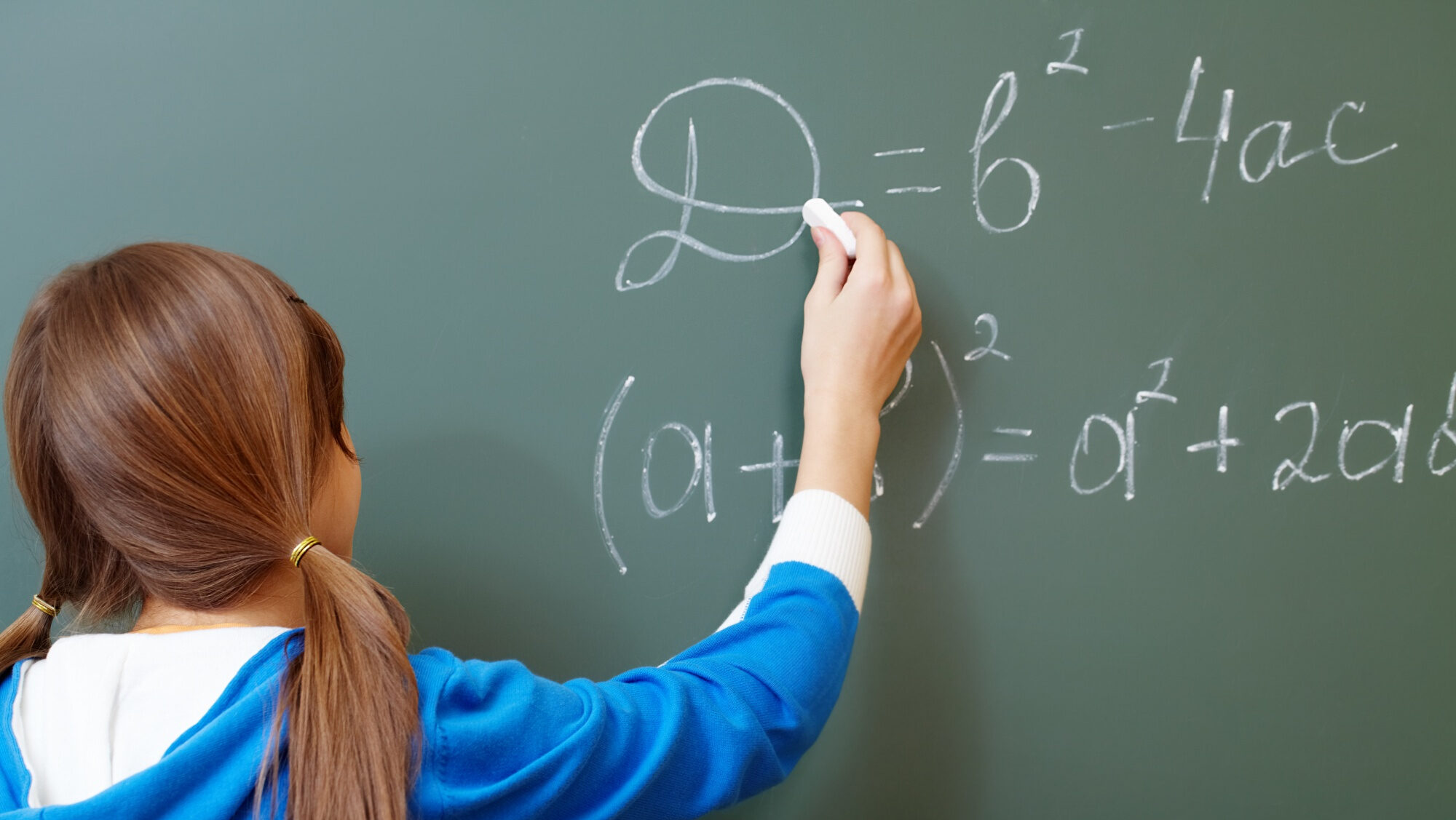 Mädchen schreibt eine mathematische Gleichung an die Tafel