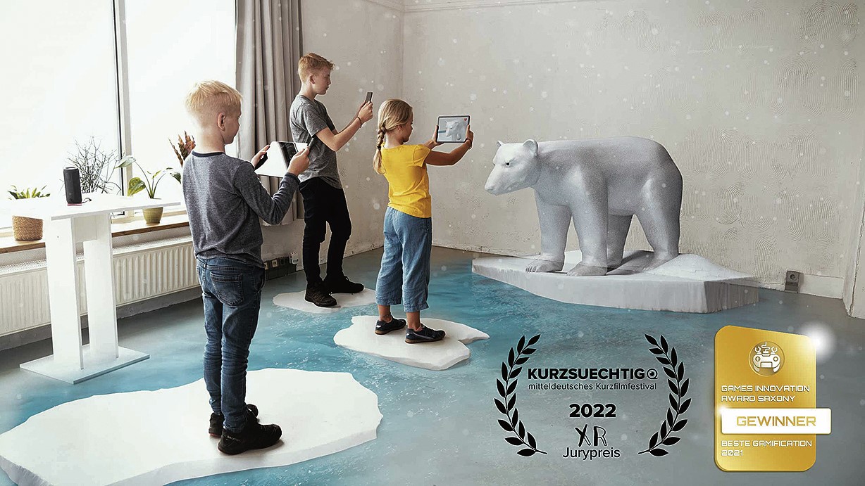 Drei Kinder stehen mit Tablets in den Händen vor einem virtuellen Eisbären