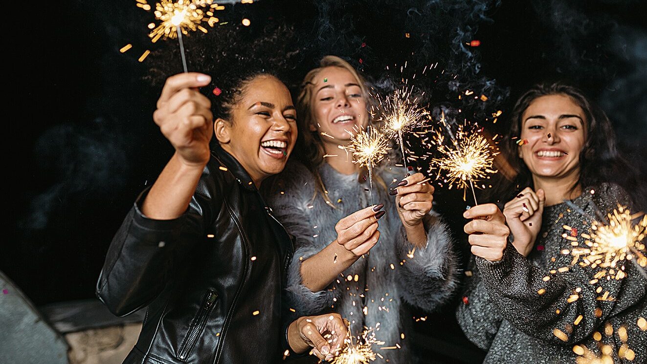 Gruppe lachender Frauen halten brennende Wunderkerzen in den Händen